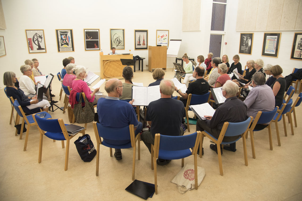 Borgere sidder i fællesskab og synger.